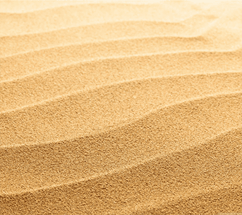 A close up of sand dunes with waves in the background