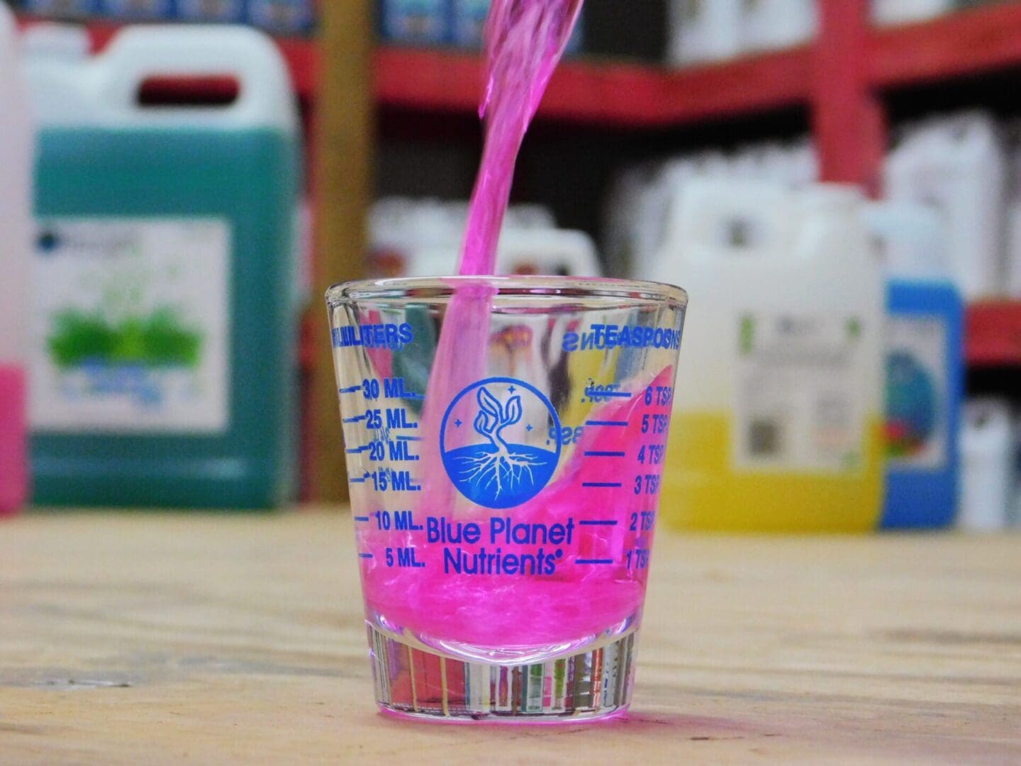 A pink liquid in a glass with a spoon.